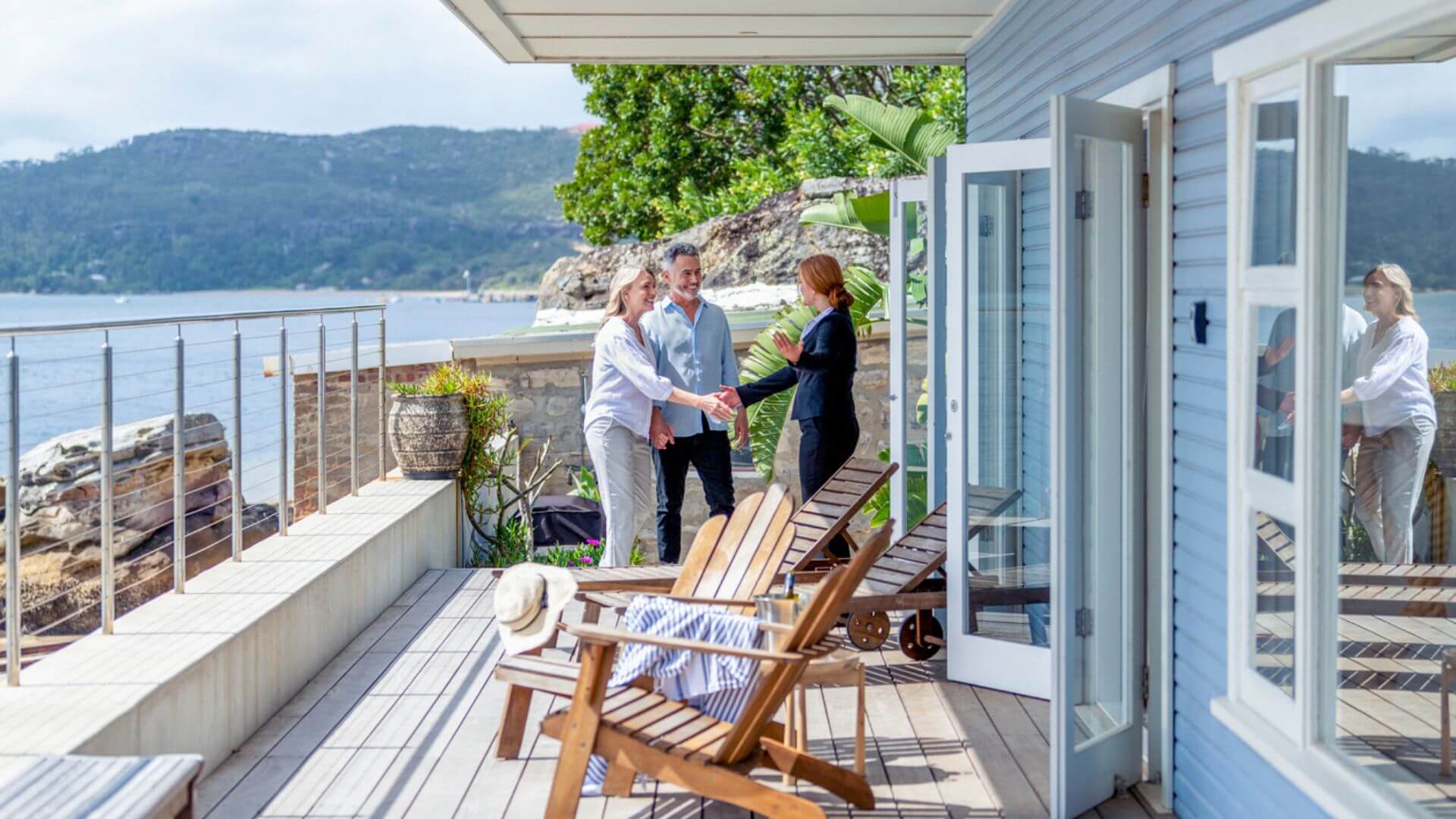 Image with couple shaking hands with a property manager who is managing their seaside investment property