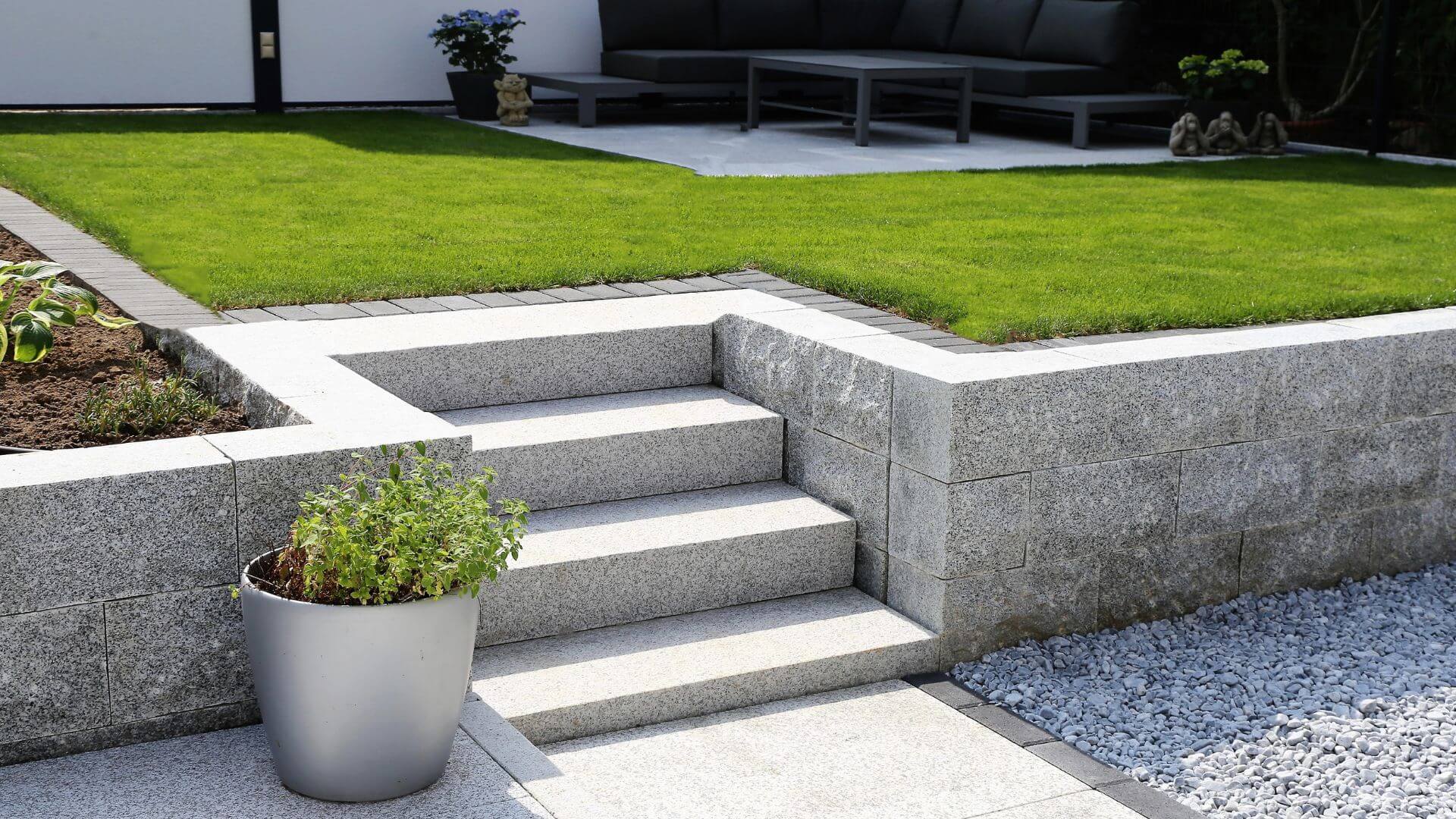 A meticulously presented outdoor space featuring pristine white steps leading up to a well-manicured lawn, bordered by a clean, modern grey retaining wall and white gravel. The polished appearance enhances the property's aesthetic, suggesting a high level of care that significantly boosts rental appeal.