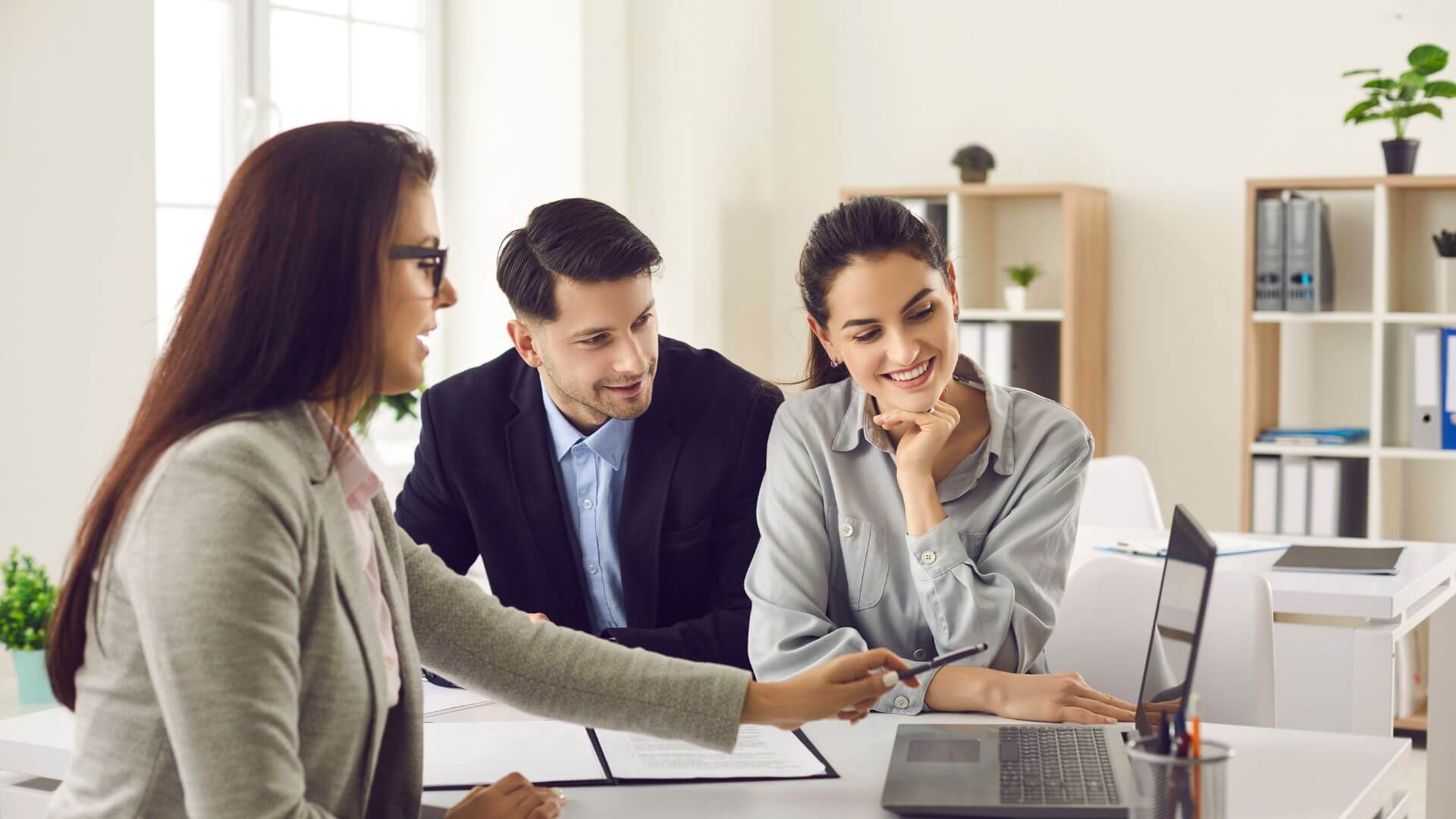 Couple meeting with a property manager to discuss investment property management options in a modern office setting