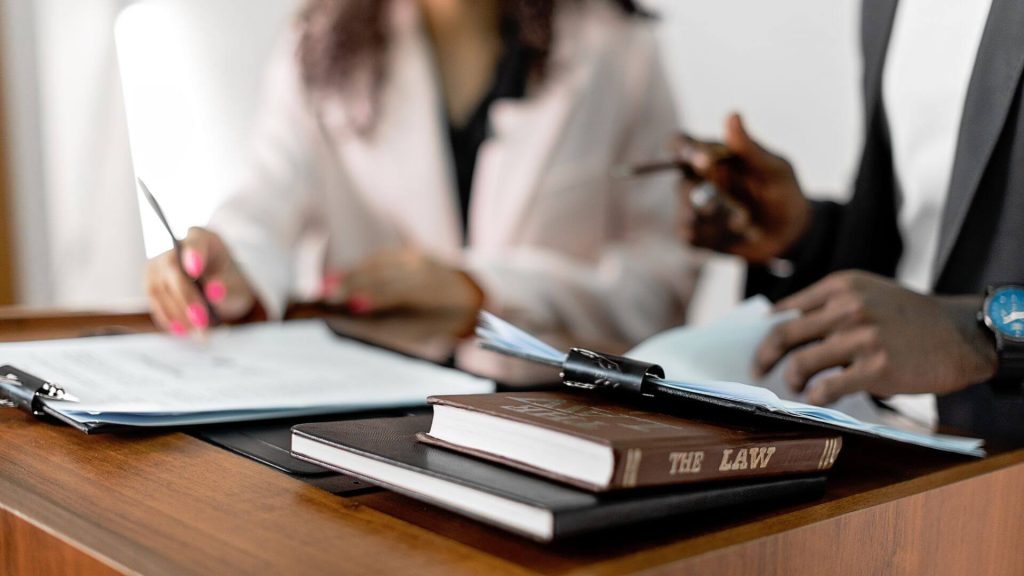 Two professionals reviewing documents at a desk, with a law book in focus—representing guidance and compliance with South Australian rental laws.