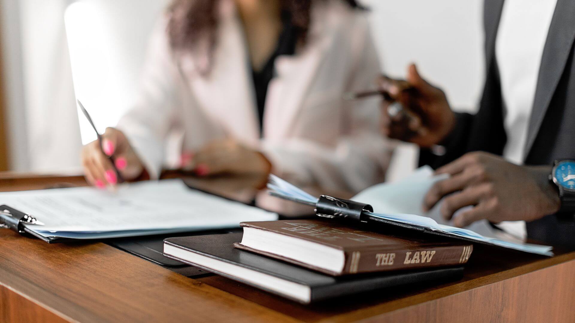 Two professionals reviewing documents at a desk, with a law book in focus—representing guidance and compliance with South Australian rental laws.