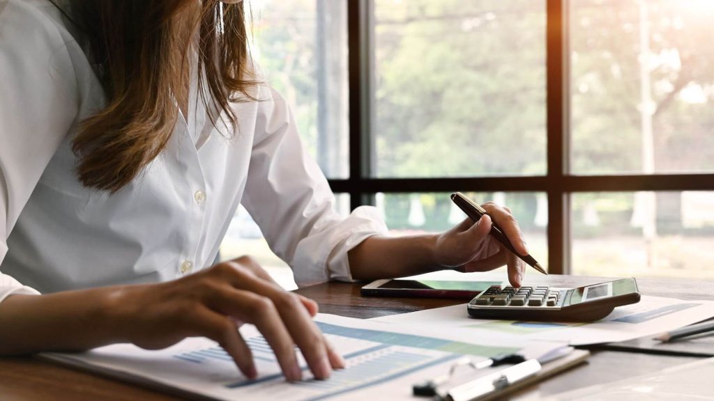 Person reviewing financial documents and using a calculator, representing research and decision-making on financing options for property investors.