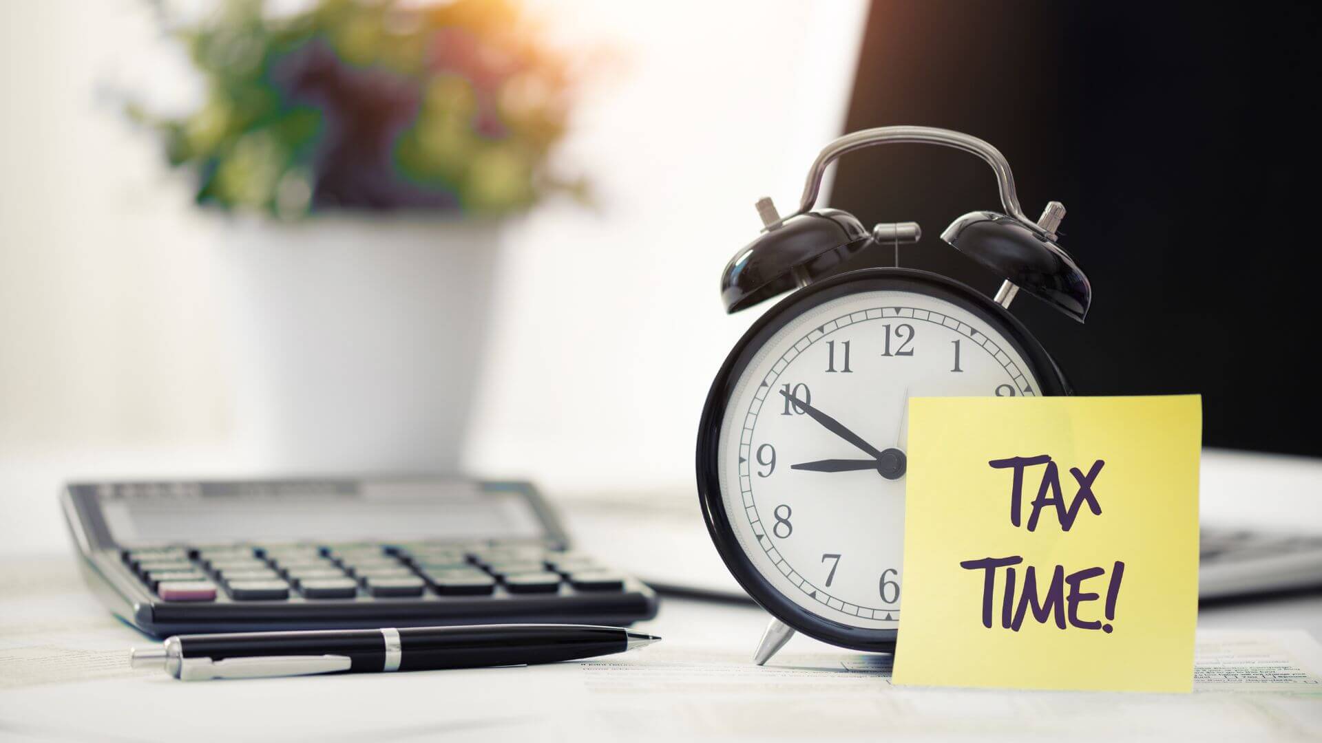 A desk setup with a calculator, pen, and alarm clock, symbolising end-of-year financial preparation, representing tax time for rental property owners and aligned with tax tips for Australian property investors.