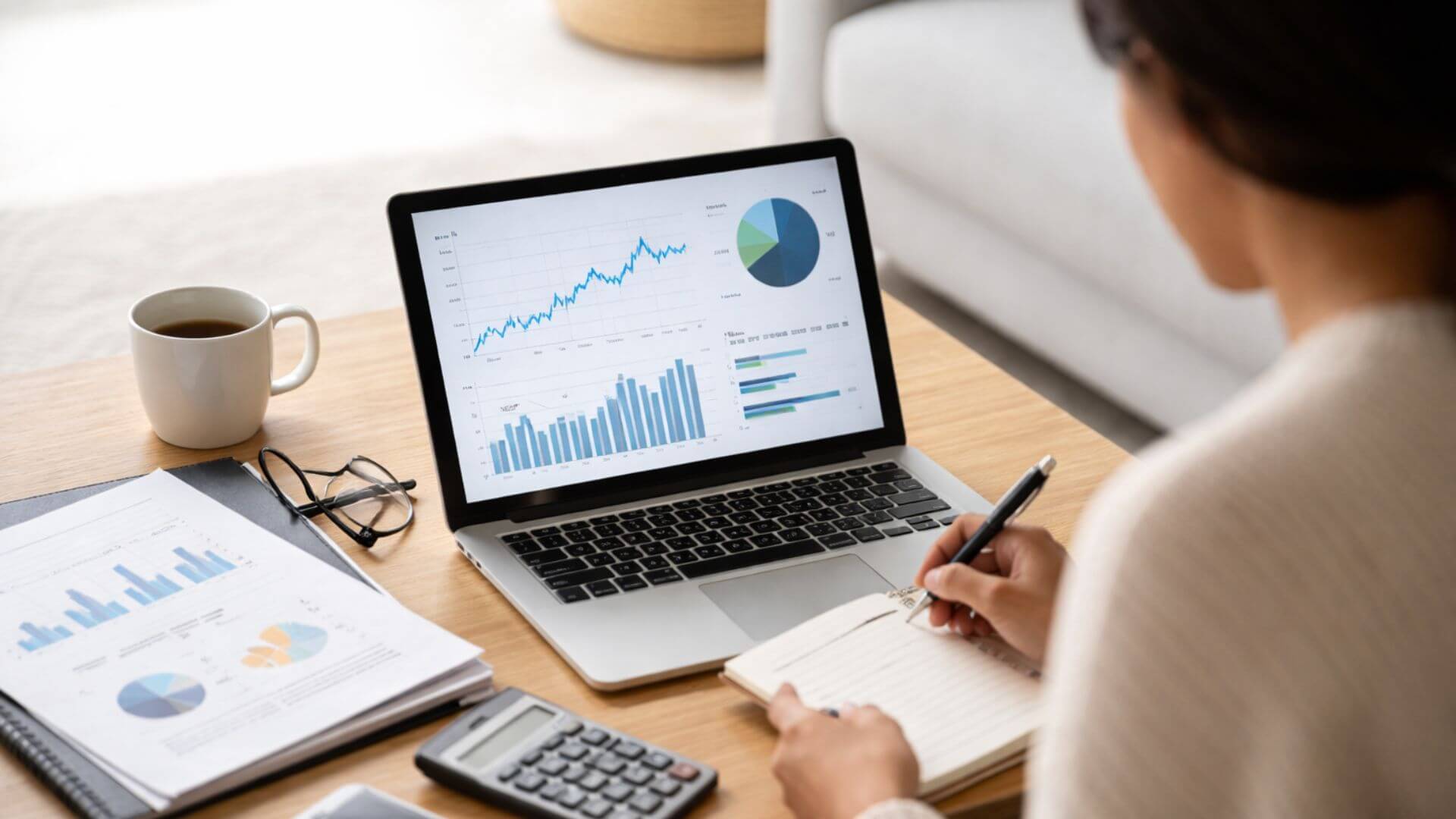 Property investor reviewing financial charts on a laptop while calculating the impact of interest rate changes on investment performance.